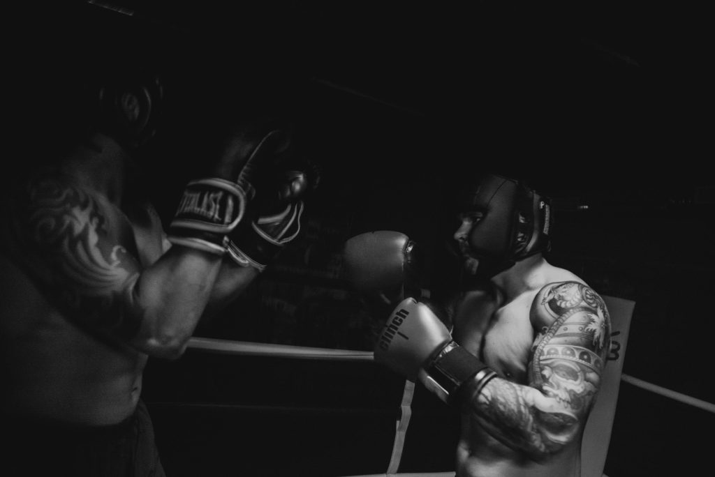 Black and white photo of two boxers sparring in a dimly lit gym, showcasing powerful action and focus.
